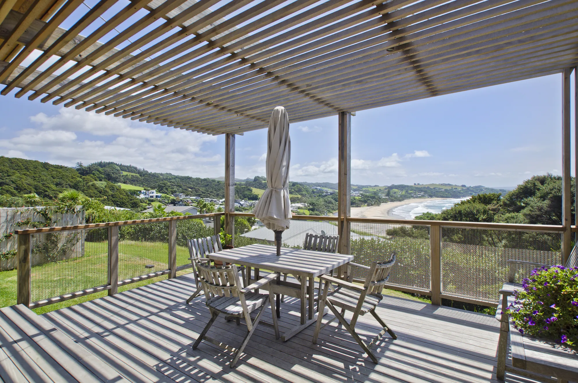 Pergola-shaded deck looking out over the beach from an architectural home