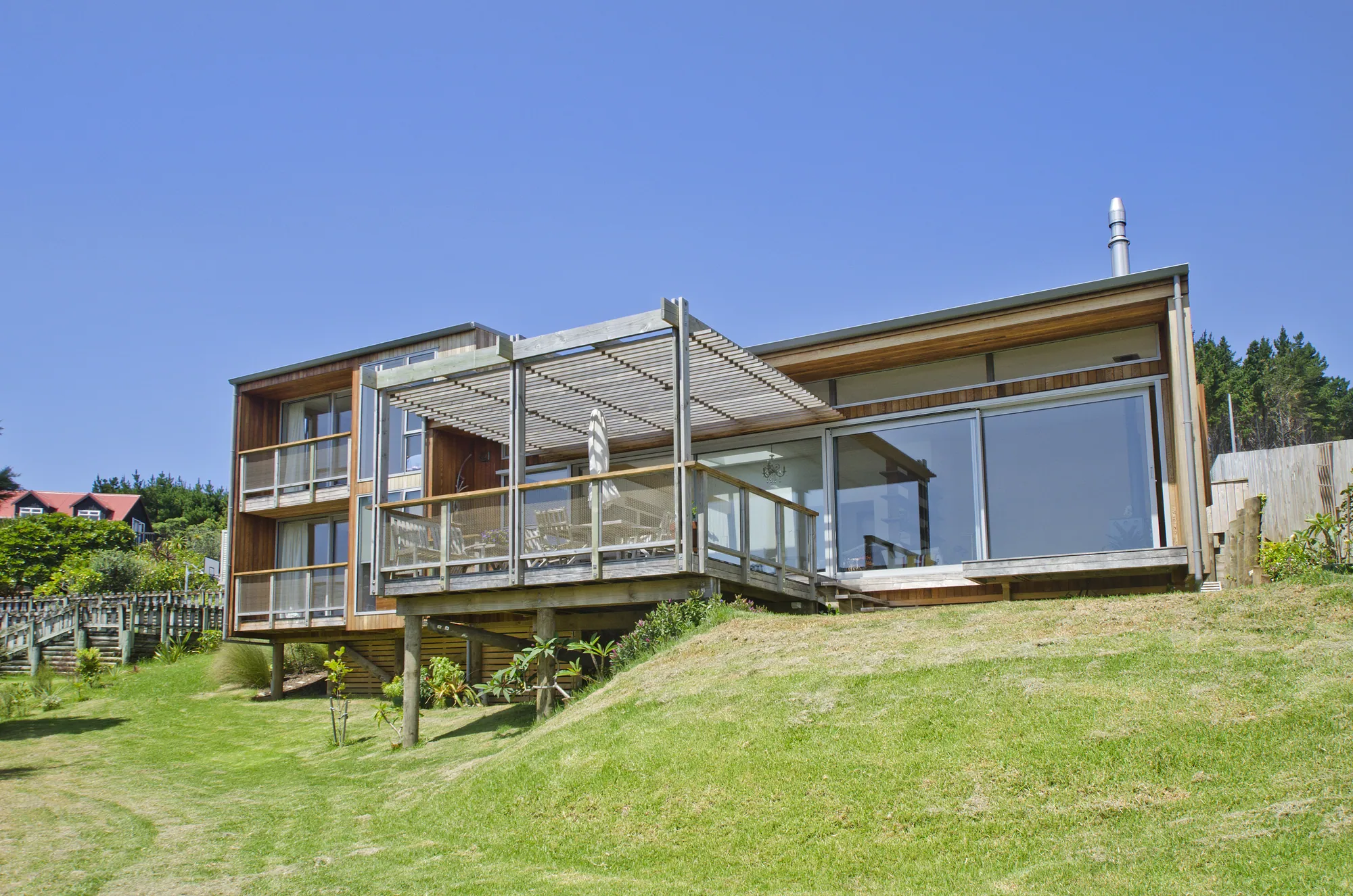 Cedar-clad architectural home elevated above a Northland surf beach