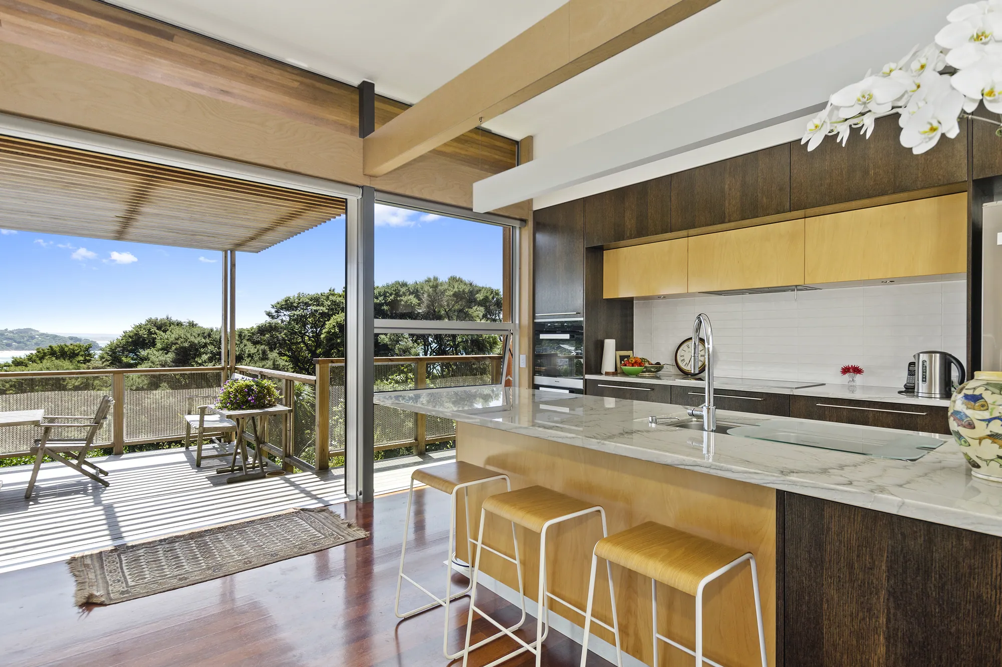 Kitchen and dining opening to the deck in a ply-lined architectural home