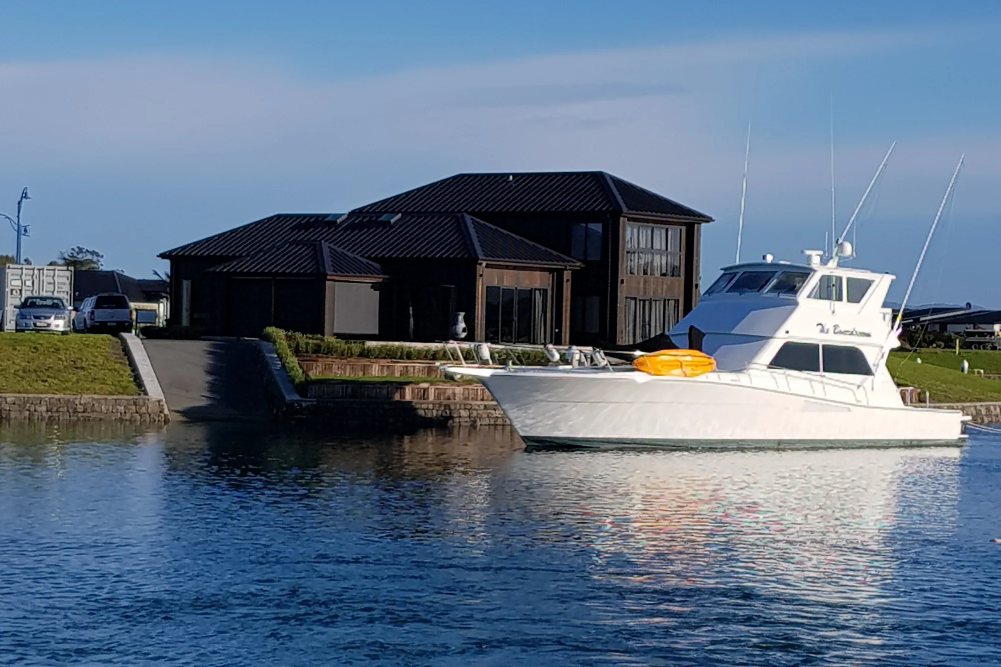 Dark-roofed canal home with a sport-fishing boat moored at its berth
