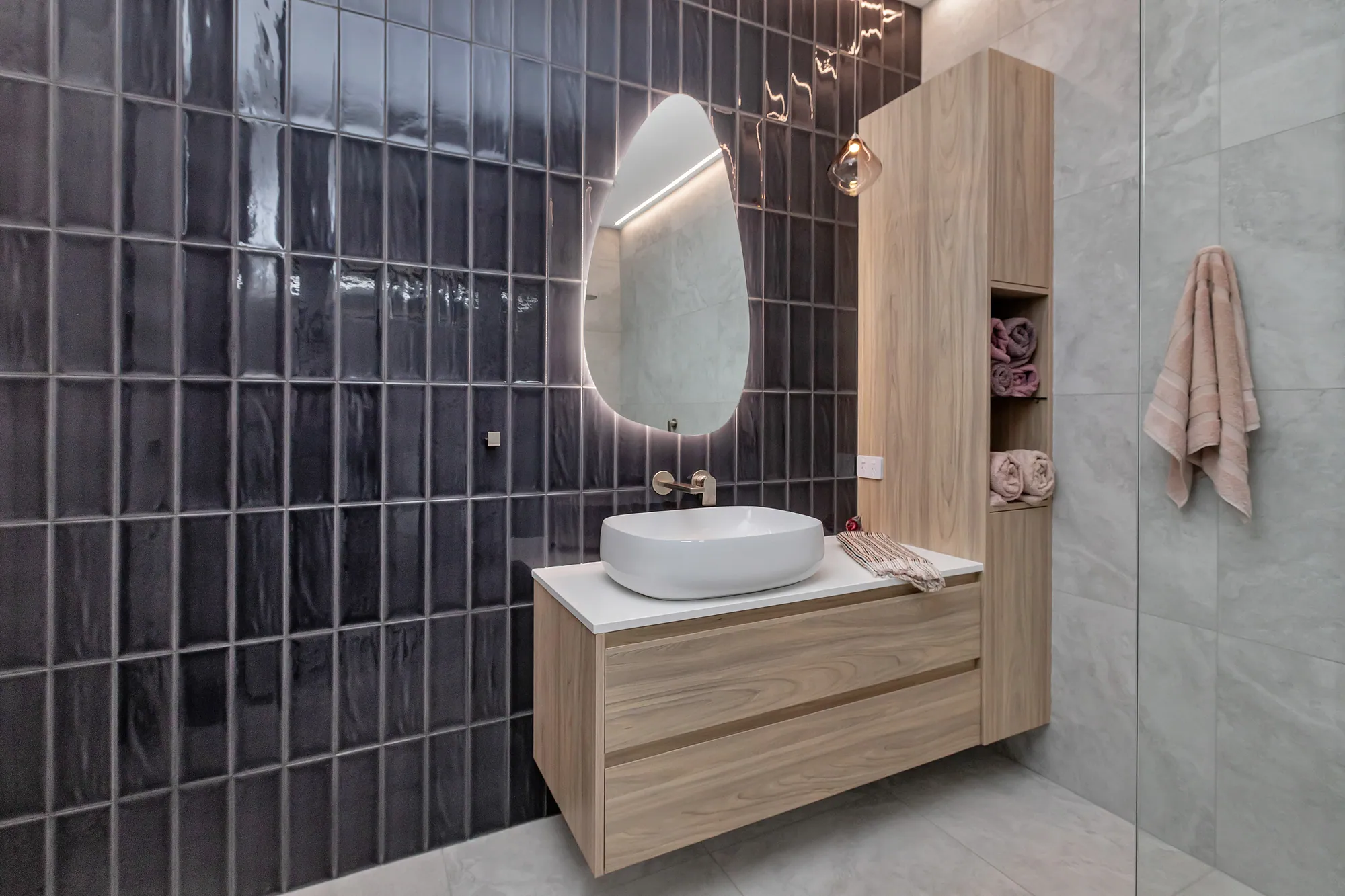 Bathroom with timber vanity and a back-lit round mirror