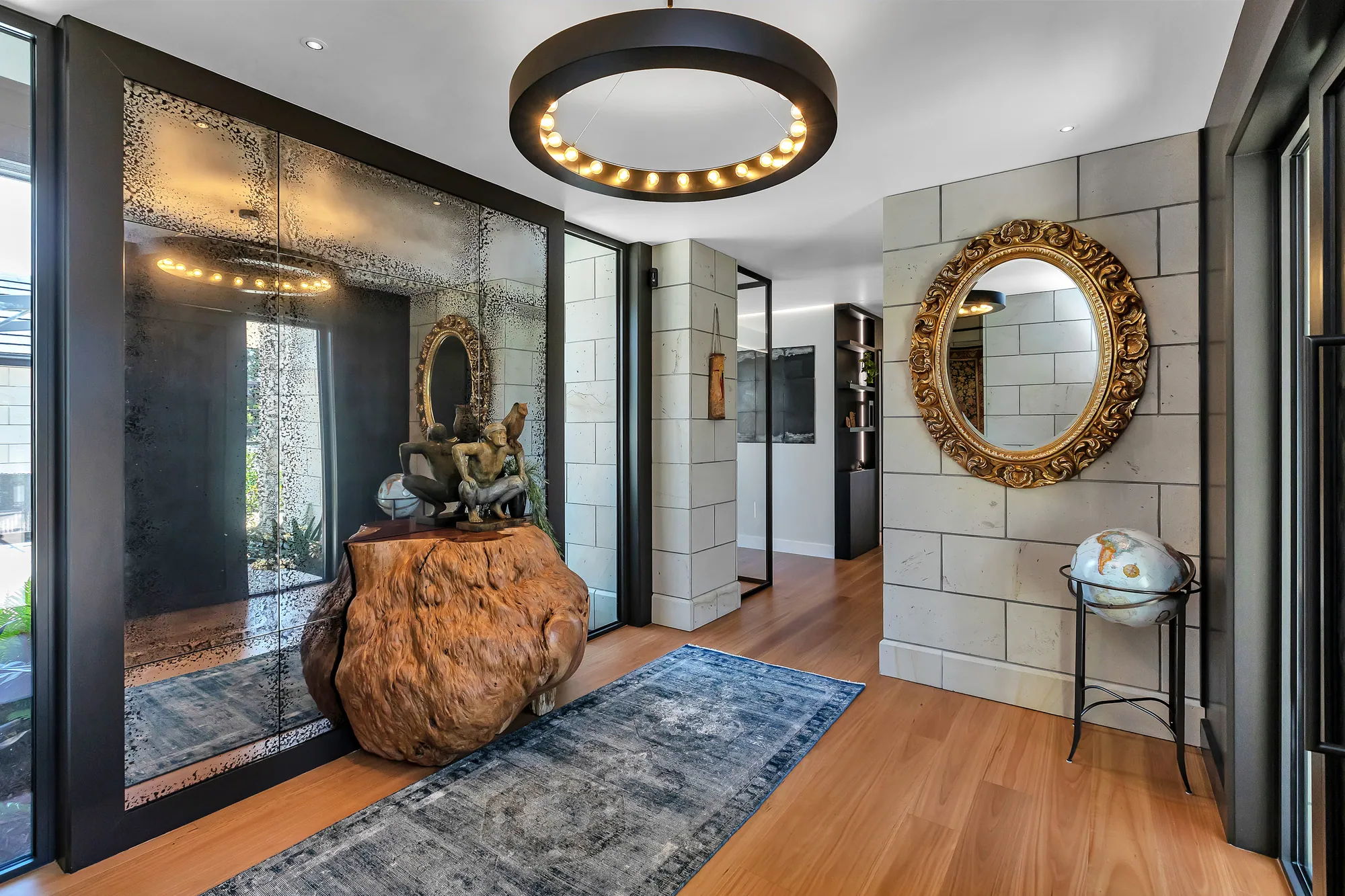 Entry hall with a round pendant light, gilt mirror and timber floor in a Waipu home