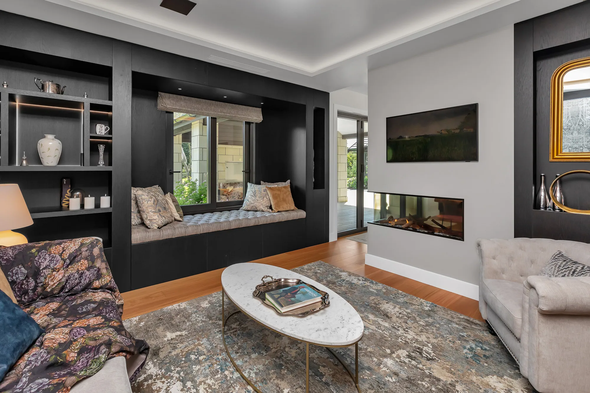 Living room with window seat and fireplace in a Waipu home