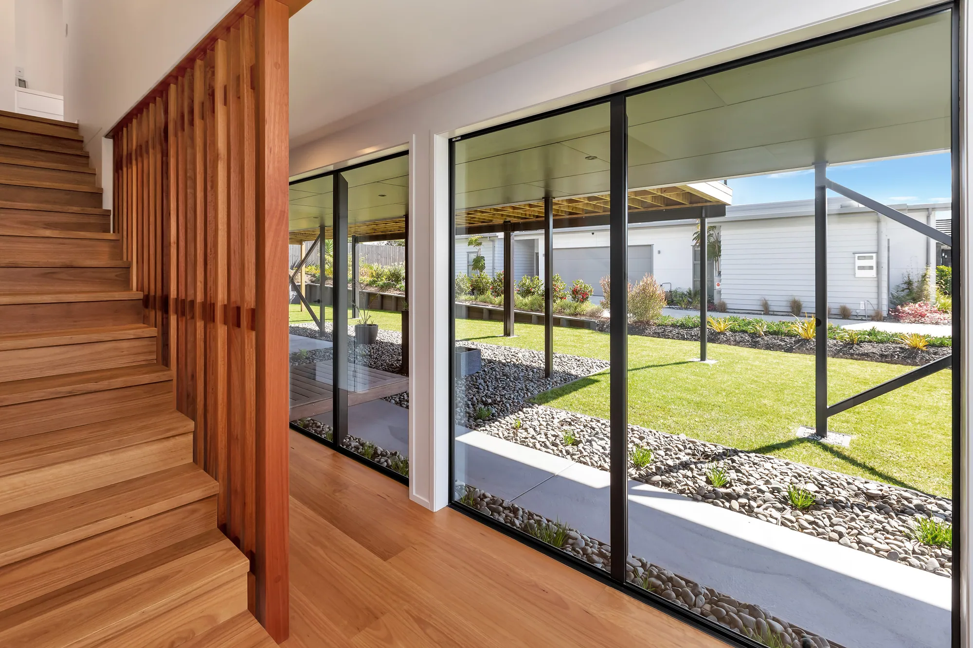 Timber stair rising beside full-height glazing