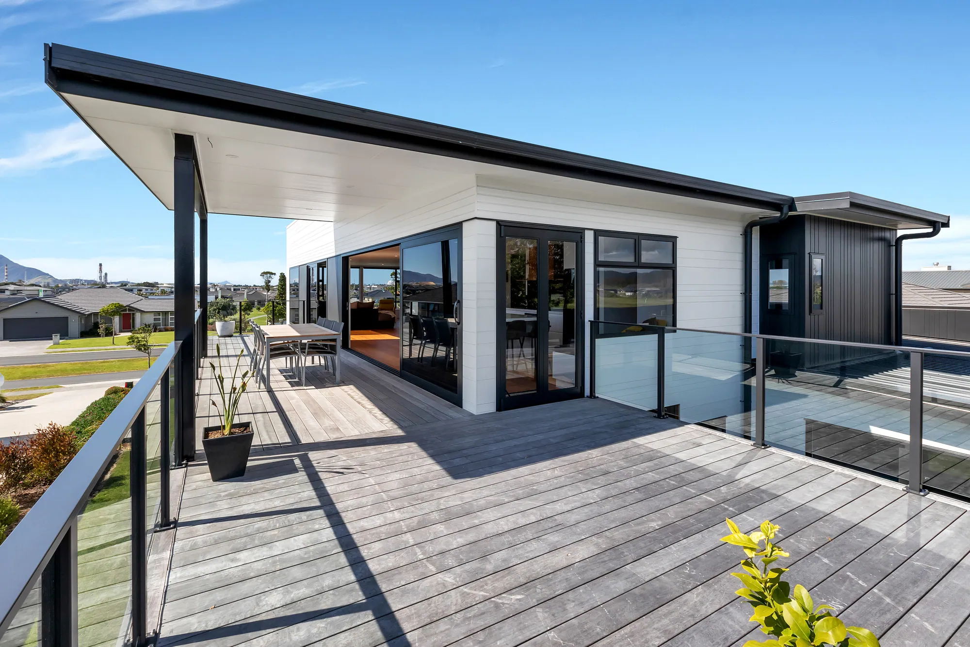 Wide covered deck with glass balustrade along a contemporary home