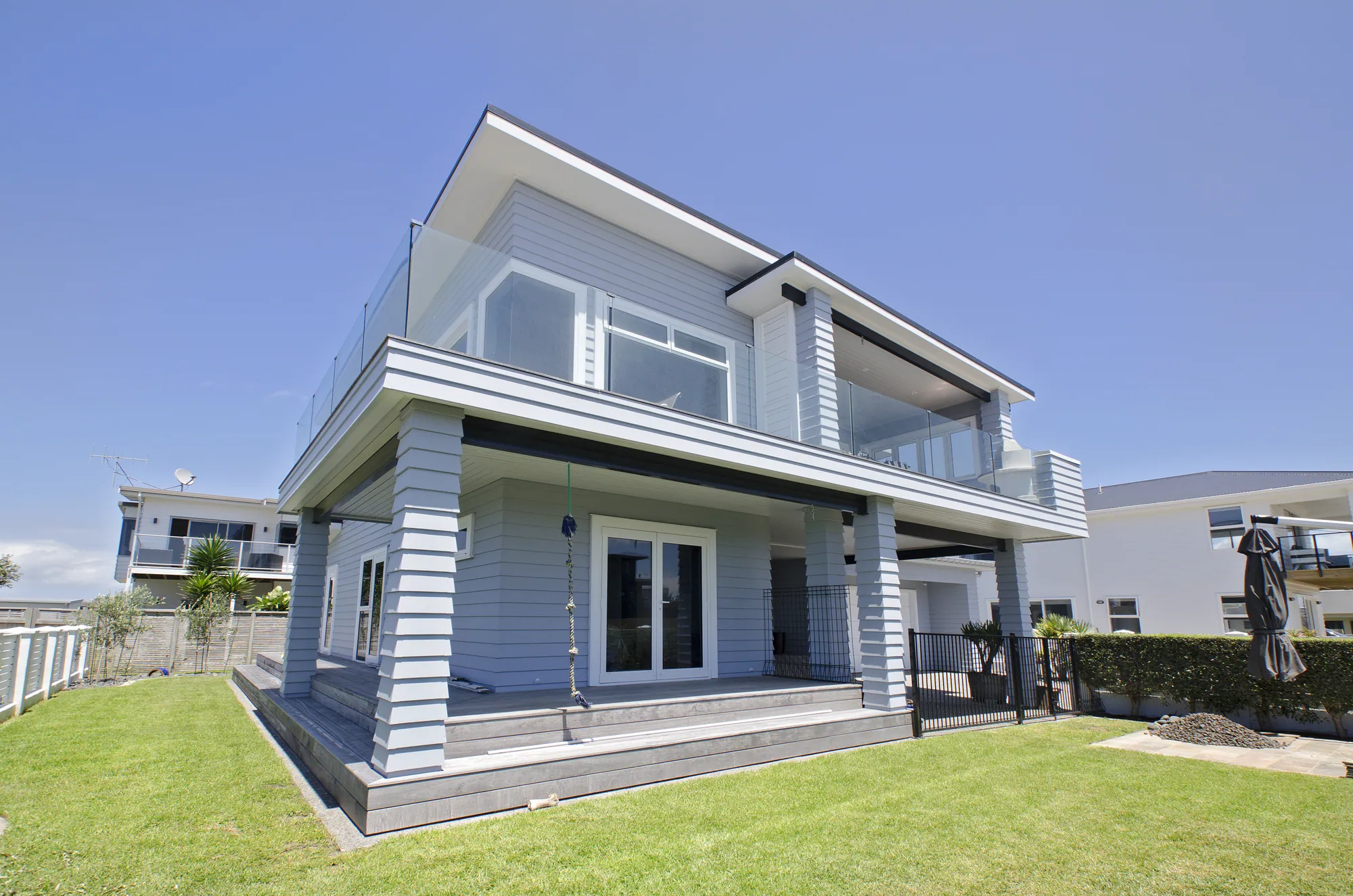 Reclad two-storey home with a covered deck and lawn