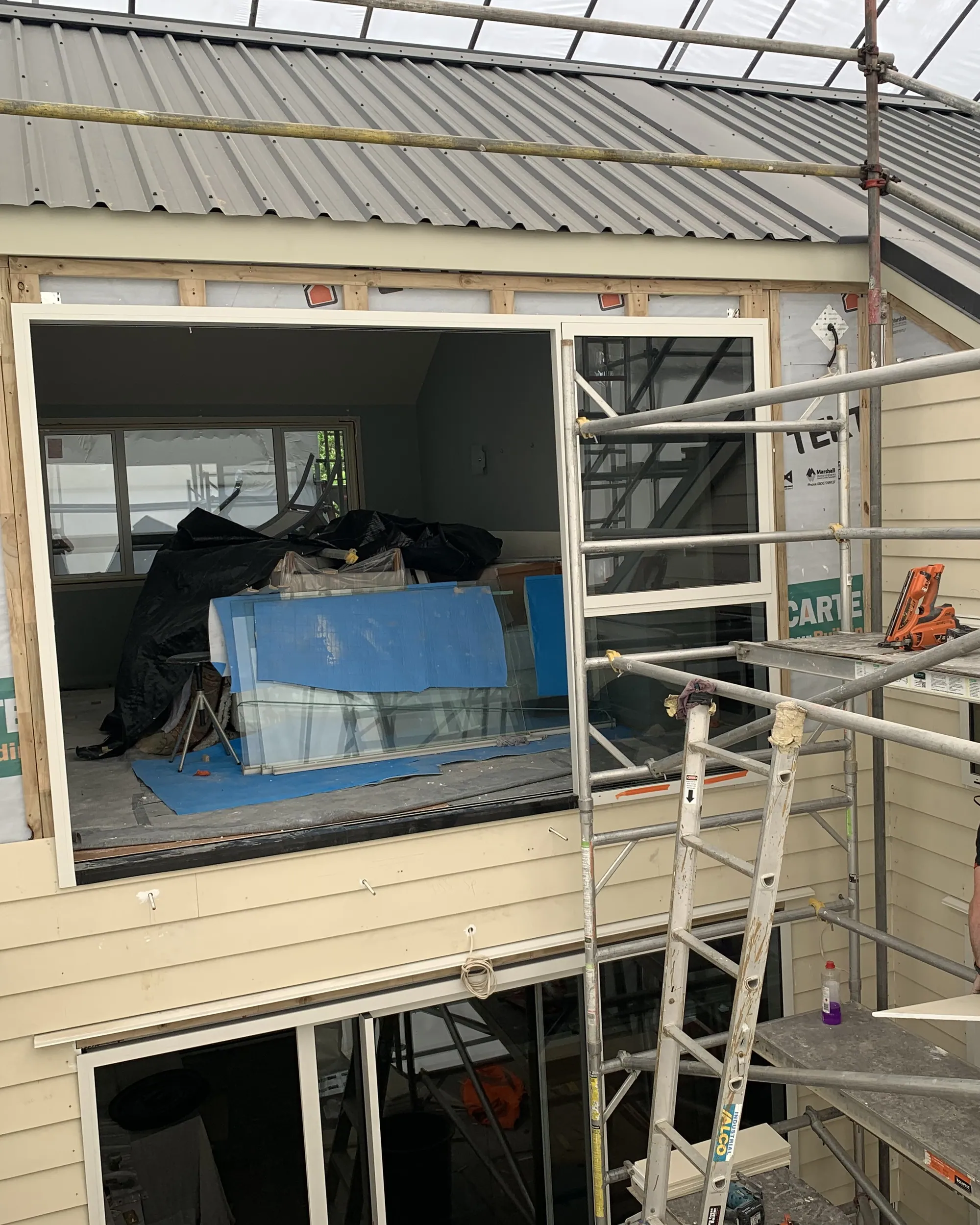 Recladding under way: scaffolding, building wrap and an opening ready for new cladding