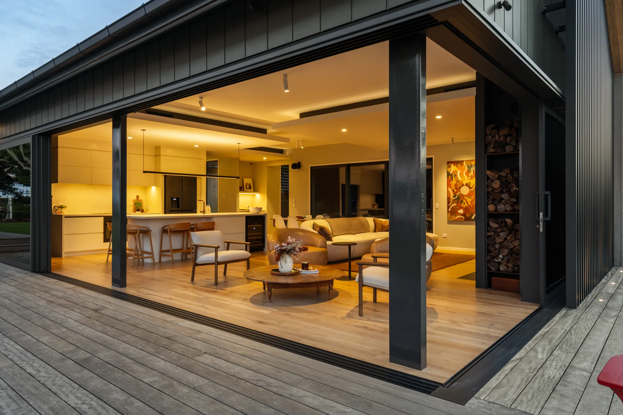 The showhome living areas open to the deck at dusk