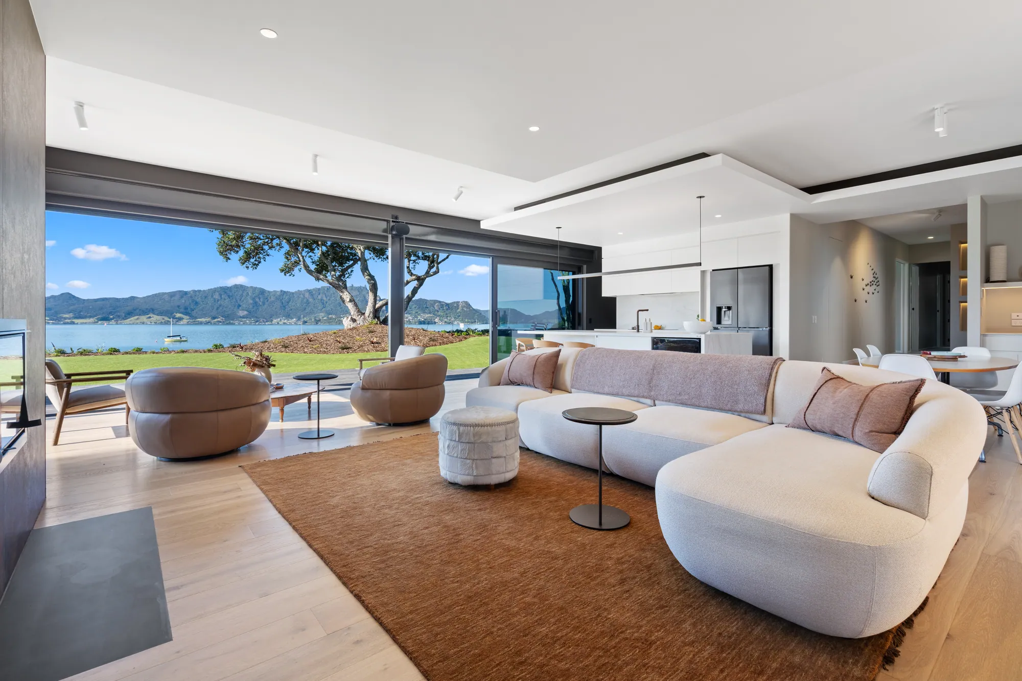 The showhome living area opening onto the lawn with the harbour beyond