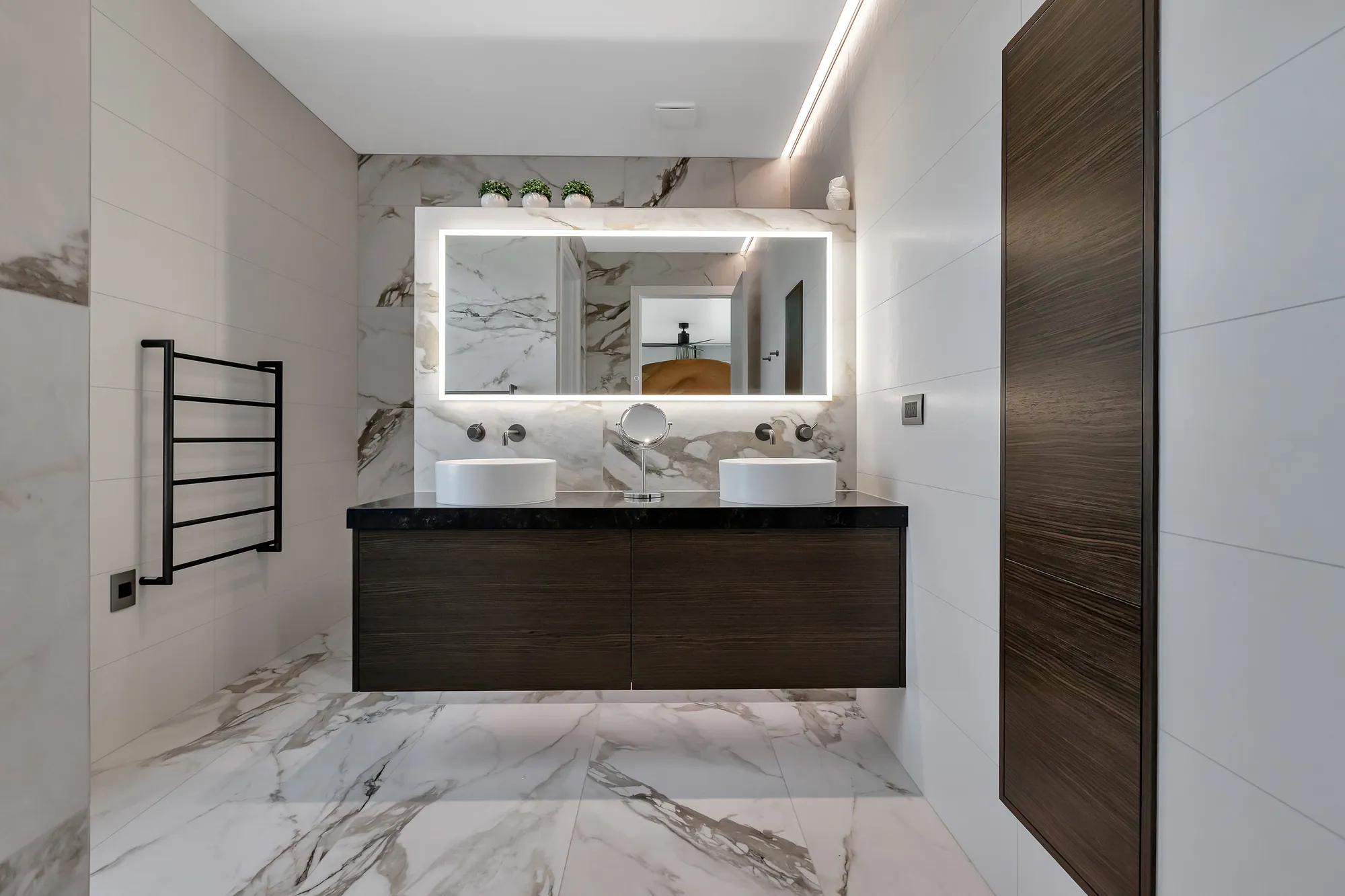 Marble bathroom with back-lit mirror and floating vanity